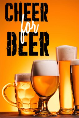 arranged mugs of cold beer with froth on orange background with 