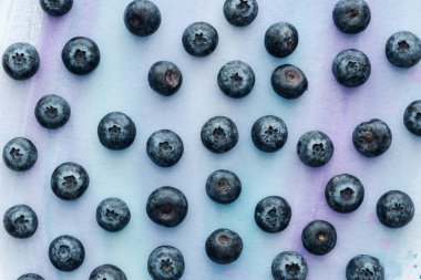 top view of ripe blueberries on white surface with purple watercolor strokes clipart