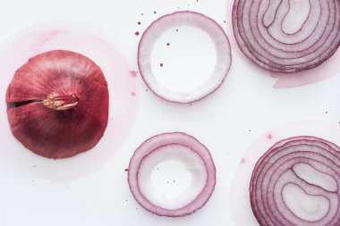 top view of red onion with slices and rings on white surface with pink watercolor blots clipart