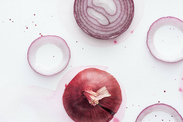 top view of sliced spicy red onion on white surface with pink watercolor blot