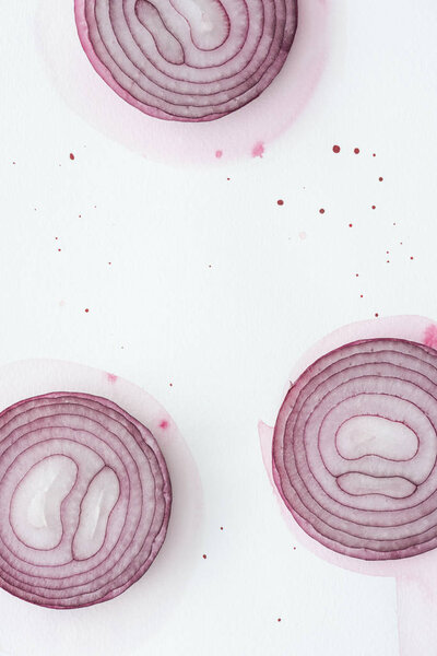 top view of sliced red onion on white surface with pink watercolor blots