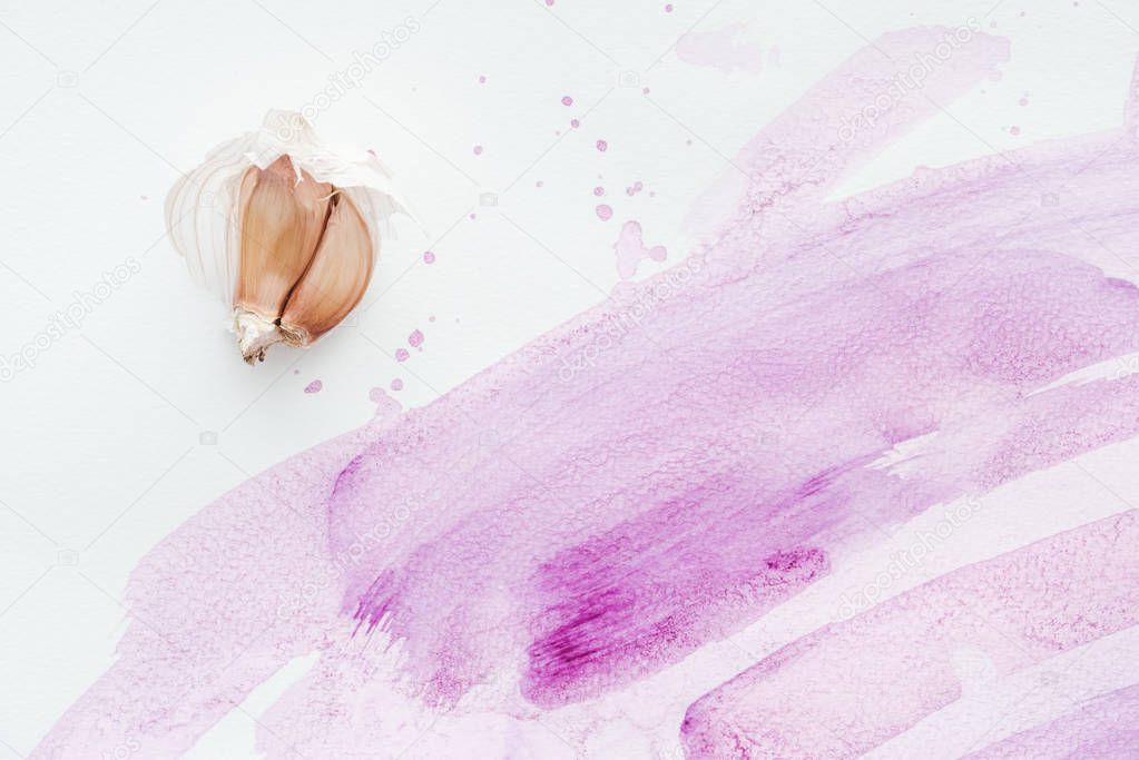top view of raw garlic on white surface with pink watercolor strokes and blots