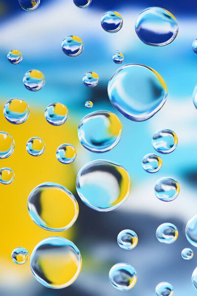 close-up view of beautiful clean water drops on blurred colorful abstract background