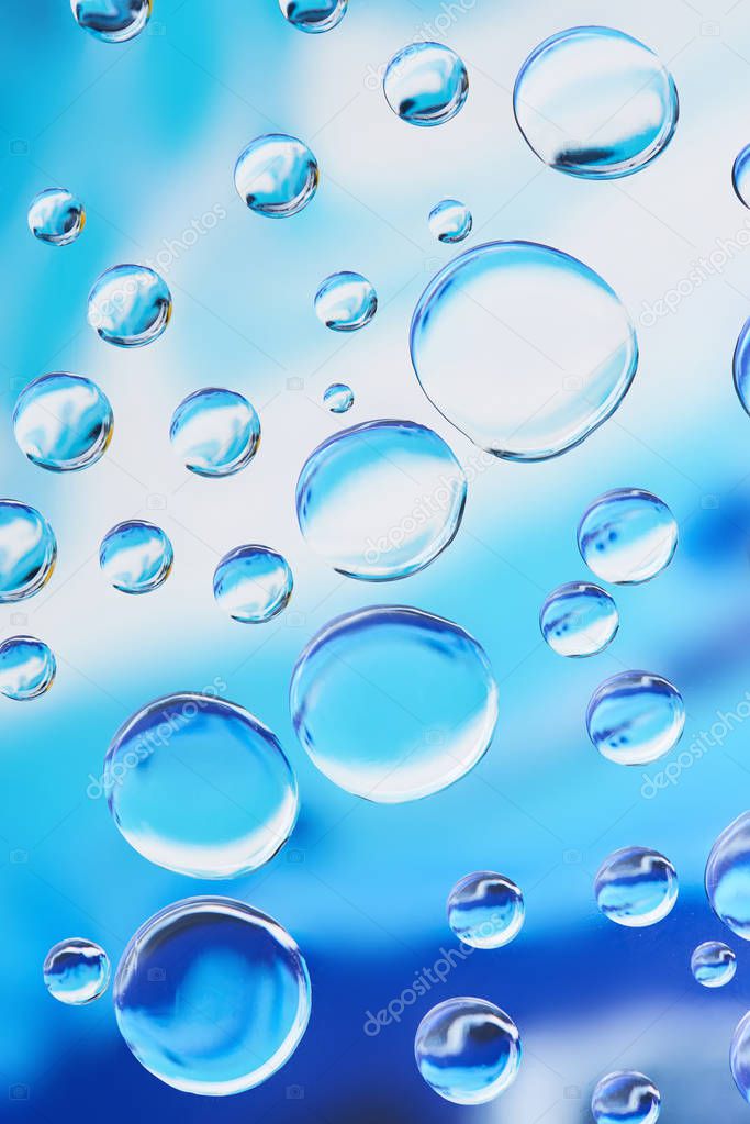 close-up view of beautiful transparent water drops on blue abstract background