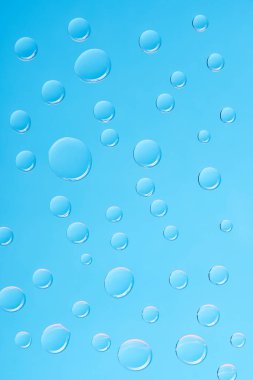 close-up view of transparent water drops on blue background clipart