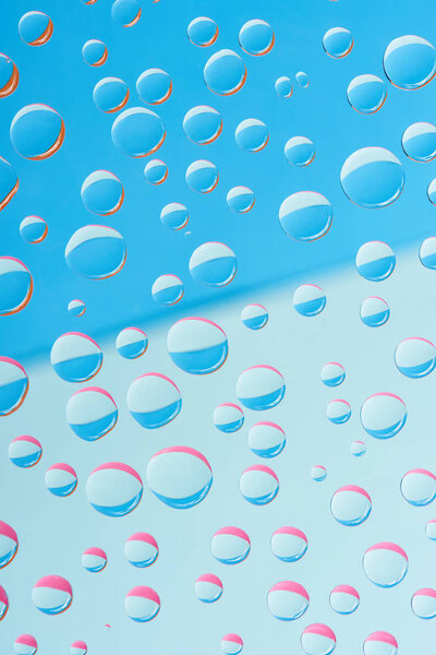 close-up view of transparent dew drops on blue abstract background 