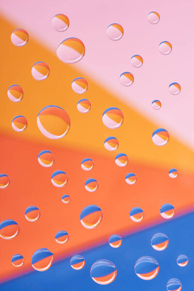 close-up view of transparent calm water drops on colorful background           
