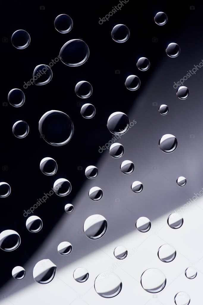 close-up view of transparent water drops on black, grey and white background