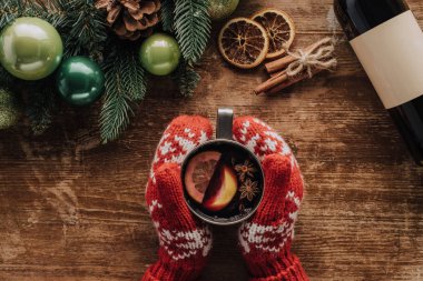 çırpı ile Noel köknar ahşap masa, mulled şarap bardak tutan kadın kırpılmış görüntü