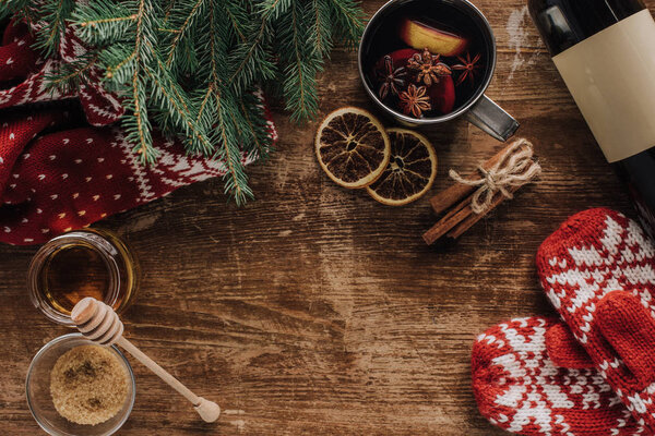 top view of mulled wine in cup and mittens on wooden tabletop, christmas concept
