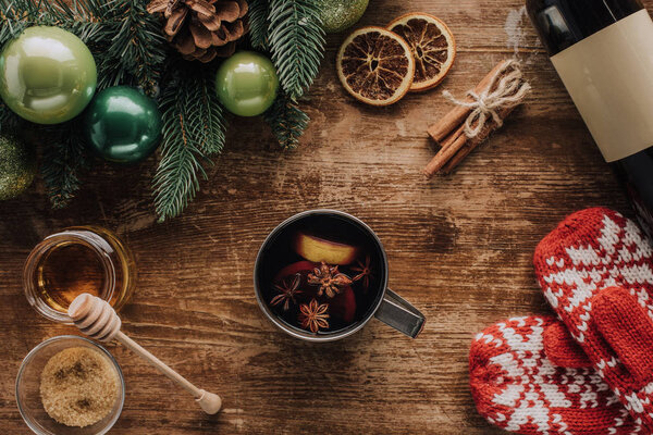 повышенный вид на чашку глинтвейна и зимние варежки на деревянном столе, рождественская концепция
