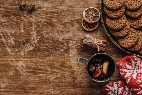 top view of mulled wine in cup, mittens and cookies on wooden tabletop, christmas concept