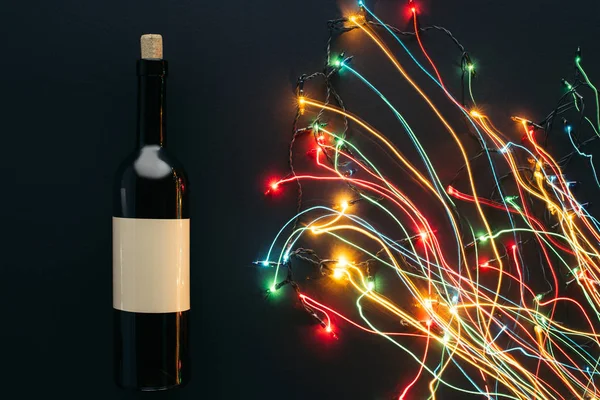 葡萄酒瓶和花环灯的高视图在黑色 圣诞节概念查出的长曝光 — 免费的图库照片