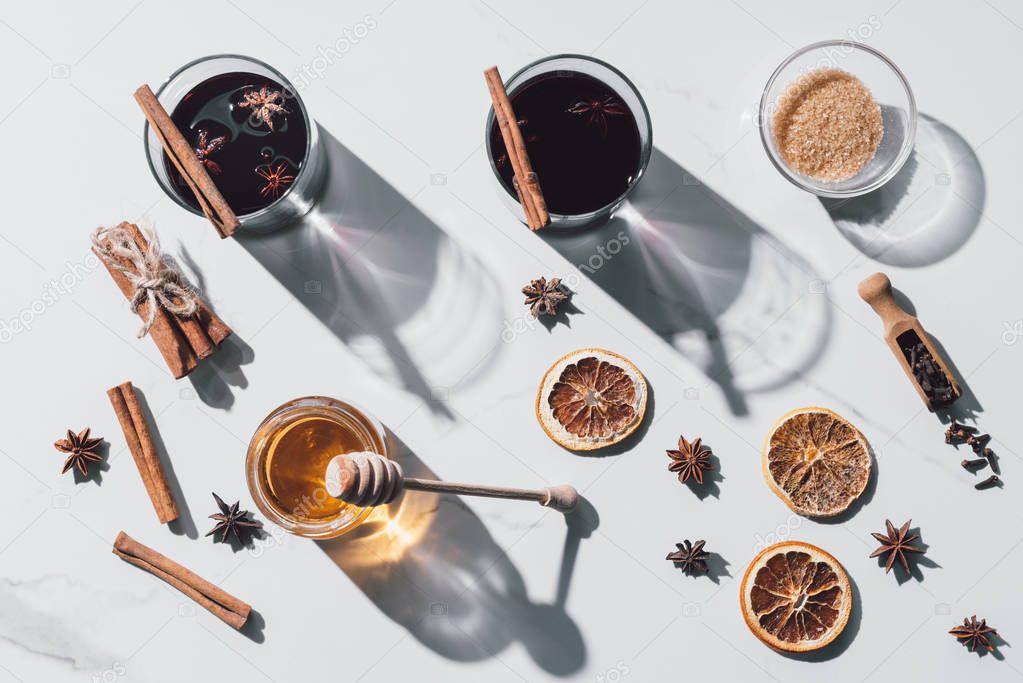 top view of glasses of mulled wine, honey and brown sugar on white tabletop