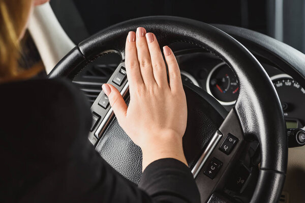 cropped shot of woman honking horn while driving car