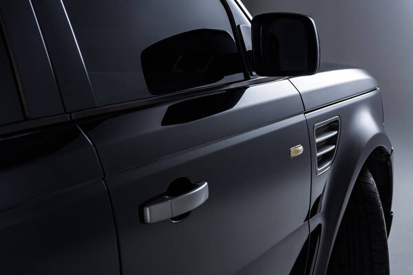 close up view of black luxury car on grey background