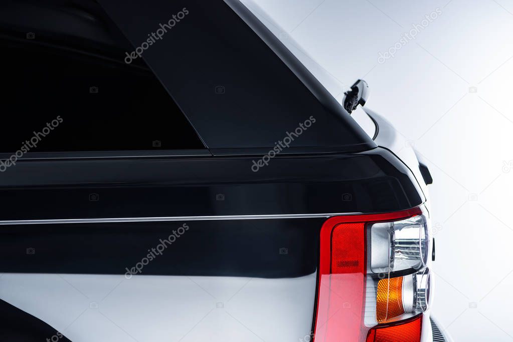 close up view of automotive head lamps of luxury black car on grey background