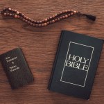 Bovenaanzicht van Heilige Bijbel met nieuwe testament en parels op houten tafel