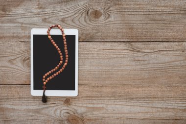 tablet ile boncuk ahşap masanın üzerinde yatan bir üstten görünüm