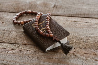 close-up shot of new testament book with beads on wooden table clipart