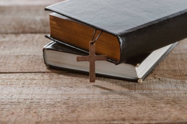 close-up shot of stacked holy bibles with cross on wooden table clipart