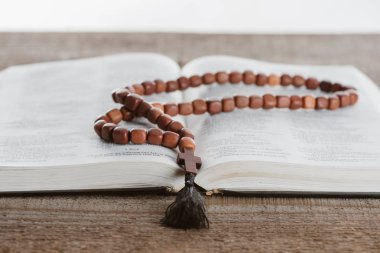 close-up shot of holy bible with beads on wooden table
