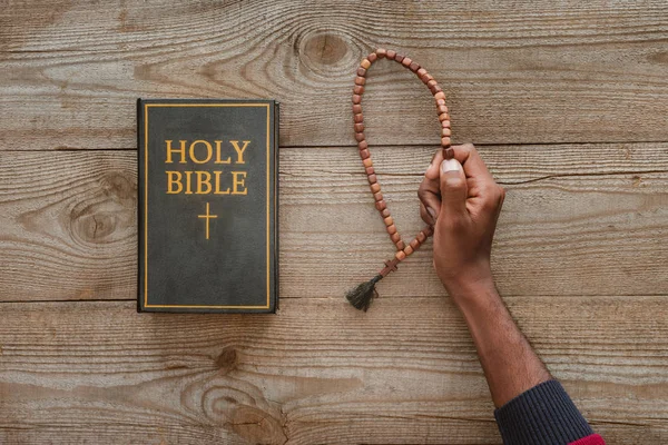 Cropped Shot African American Man Holding Beads Holy Bible Wooden — Free Stock Photo