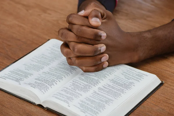 Recortado Disparo Hombre Afroamericano Rezando Con Sagrada Biblia Mesa Madera —  Fotos de Stock