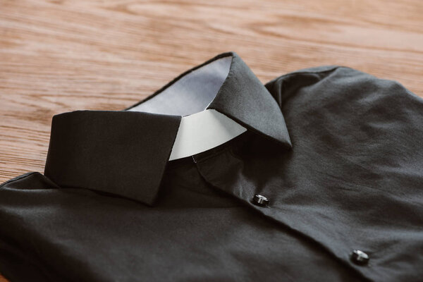 close-up shot of clerical shirt with white collar on wooden surface