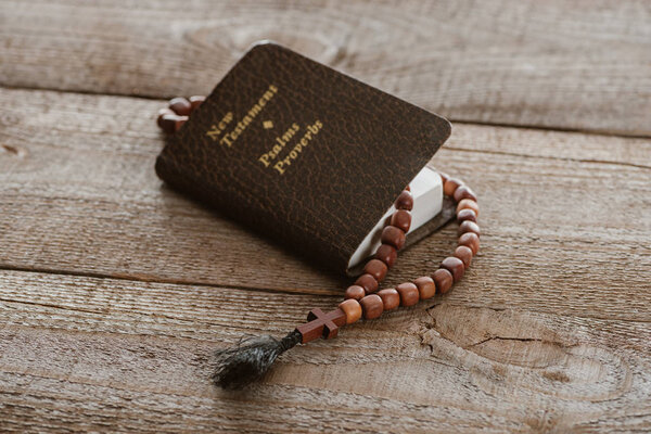 close-up shot of new testament book with beads on wooden surface