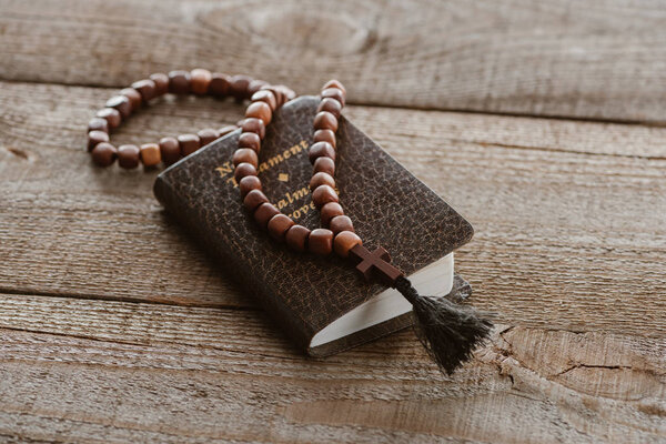 close-up shot of new testament book with beads on wooden table
