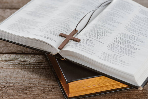 close-up shot of holy bibles with cross on wooden table