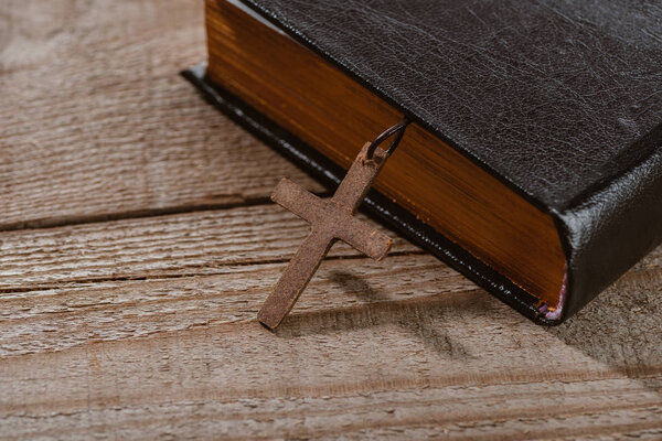 close-up shot of holy bible with cross on wooden table