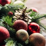 Vue rapprochée de couronne de pins avec des boules de Noël rouges et dorées sur fond en bois