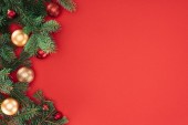 plochý ležela s borové větve stromů s červenými a zlatými vánoční koule izolované na červené