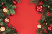 flache Lage mit Tannenzweigen mit roten und goldenen Weihnachtskugeln isoliert auf rot