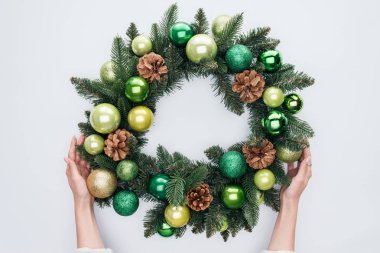 kırpılmış yeşil oyuncaklar üzerinde beyaz izole ile Noel çelenk tutan kadın görüntüsünü