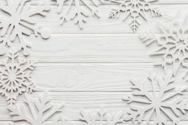 flat lay with decorative snowflakes on white wooden tabletop with blank space in middle clipart