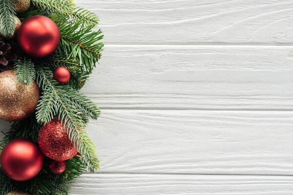 top view of wreath with red christmas toys on white wooden surface
