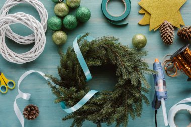 mavi ahşap masa üzerinde görücü usulü Çam ağaç dalları ve süslemeler el yapımı Noel çelenk için üstten görünüm
