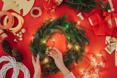 El yapımı Noel çelenk ışıkları kırmızı arka plan ile dekorasyon kadının kısmi görünümü