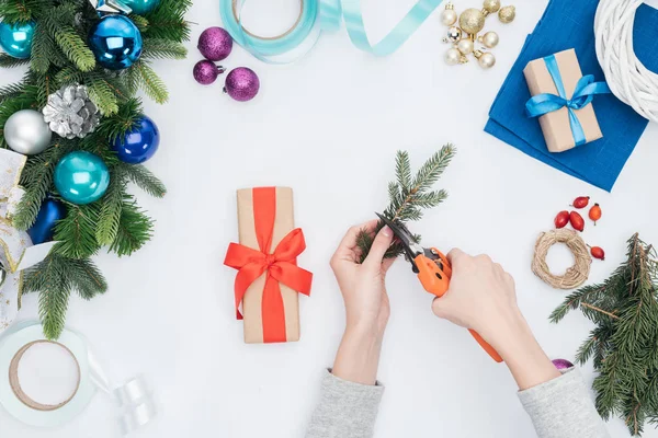 Teilansicht Einer Frau Die Weihnachtsgeschenk Mit Tannenzweig Auf Weiß Verziert — kostenloses Stockfoto