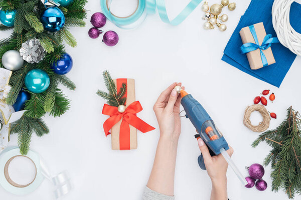 partial view of woman decorating wrapped present with christmas ball isolated on white