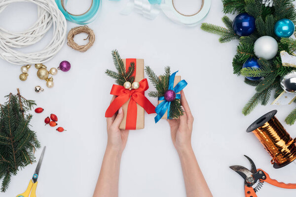 partial view of woman holding wrapped christmas gifts in hands isolated on white