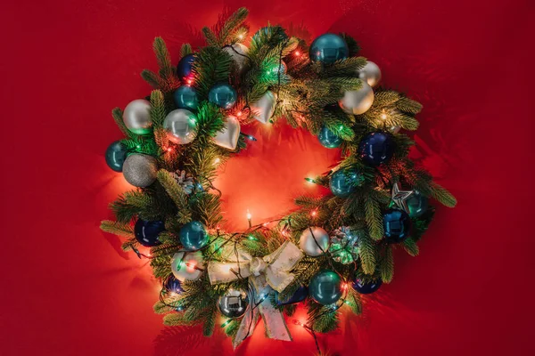 おもちゃと赤い背景のライトで飾られたクリスマスの花輪の上から見る — ストック写真