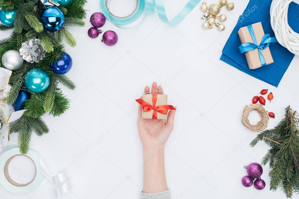 partial view of woman holding wrapped christmas gift with red ribbon isolated on white