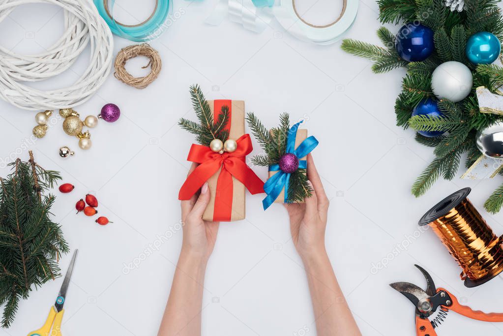 partial view of woman holding wrapped christmas gifts in hands isolated on white