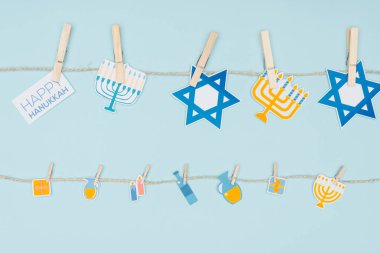 top view of hannukah holiday paper signs pegged on rope isolated on blue, hannukah concept clipart
