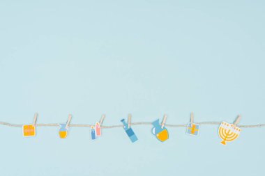 top view of hannukah holiday paper signs pegged on rope isolated on blue, hannukah concept clipart
