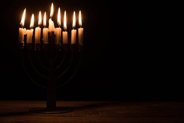 close up view of menorah with candles for hannukah holiday celebration on wooden tabletop on black background, hannukah concept clipart